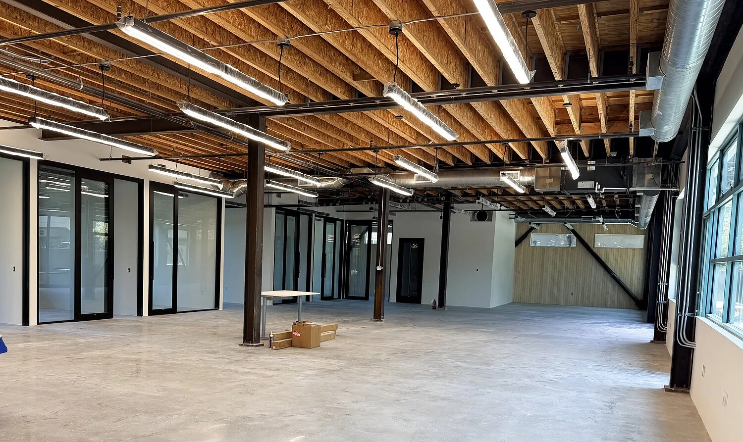 Ground-floor creative space at 1447 Cloverfield — glass-walled offices and exposed wood ceilings
