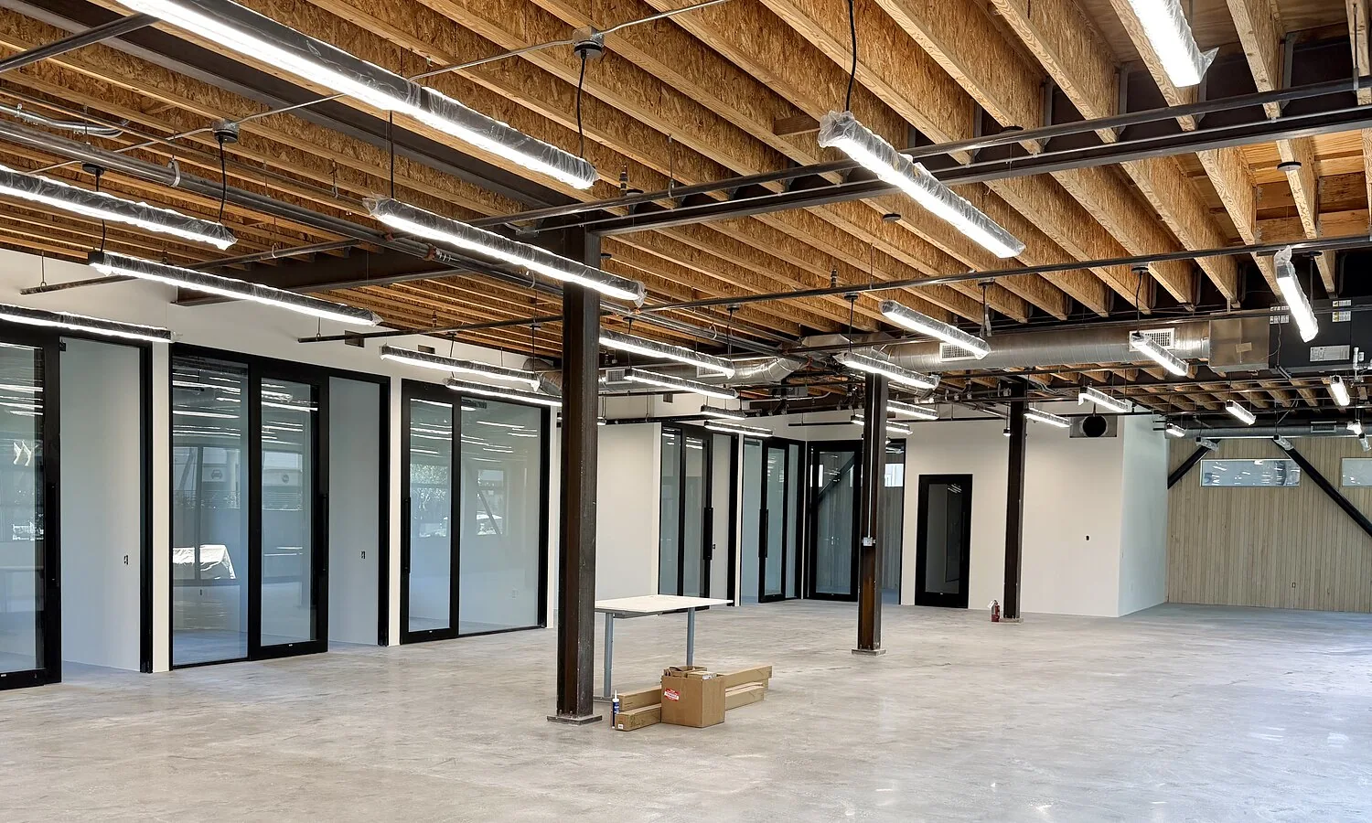 Inside 1447 Cloverfield — glass-walled offices and exposed wood ceilings
